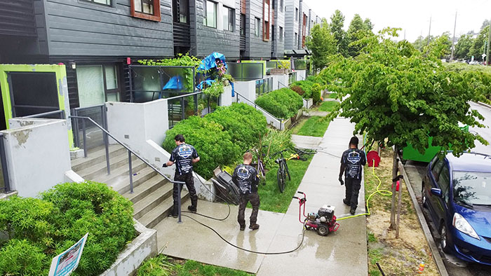 clean squad property services members performing pressure washing on strata
